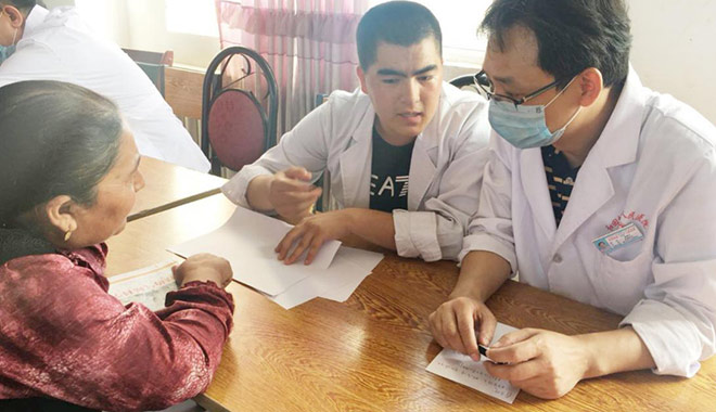 圖為曾建平醫(yī)師(右)下鄉(xiāng)義診