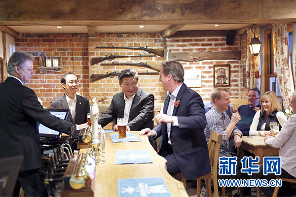 這是會晤結(jié)束后，習近平在卡梅倫陪同下乘車前往當?shù)匦℃?zhèn)體驗酒吧文化。新華社記者 鞠鵬 攝